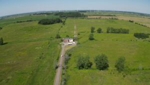 green farm field, radio tower, dilapidated building